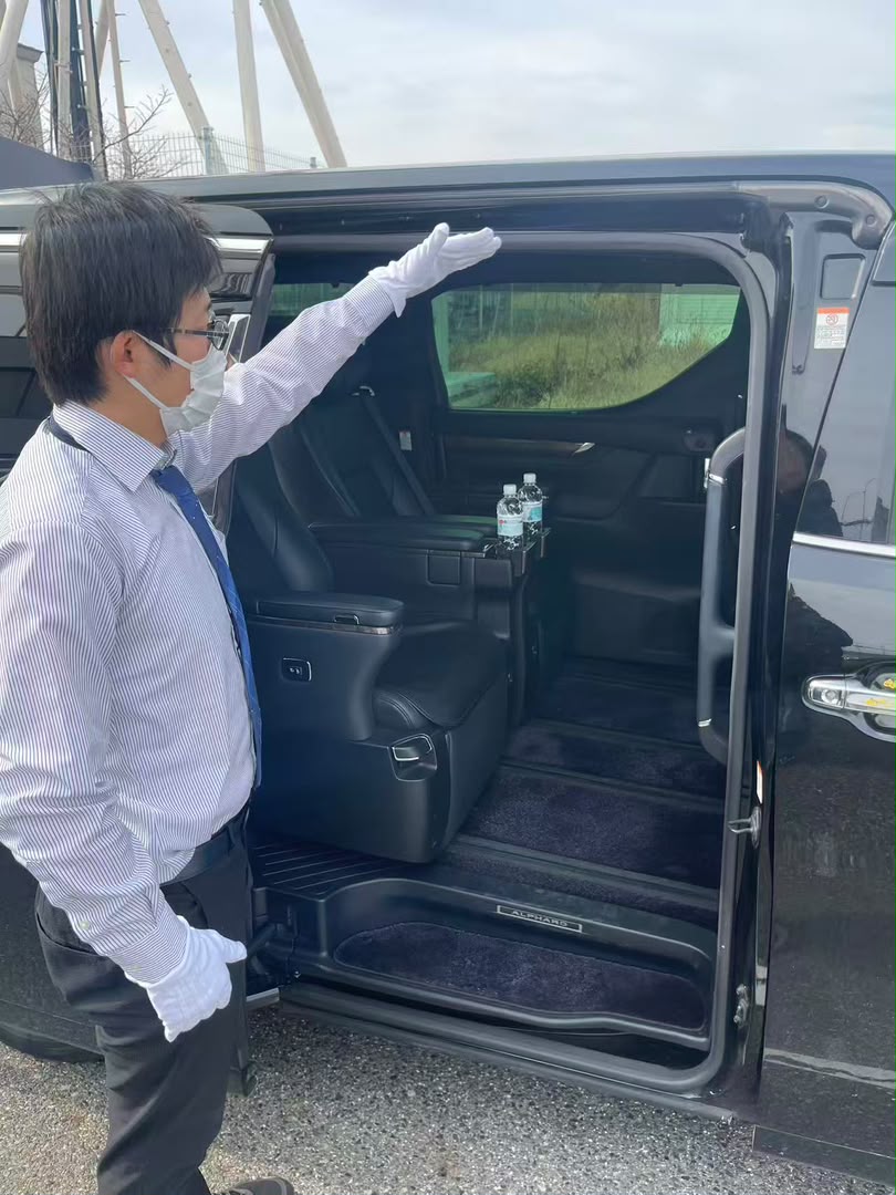 Professional driver assisting passengers into a Toyota Alphard